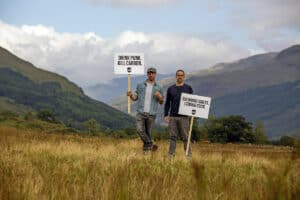 Company Founders holding placards in field to promote new BrewDog Forest.