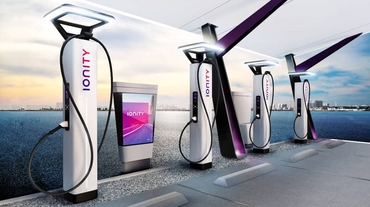 Artist's impression of branded IONITY electric vehicle charging stations pictured against waterfront cityscape backdrop.