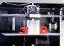 Close-up of 3D printer in black and white, with plastic '3' and 'D' in red.