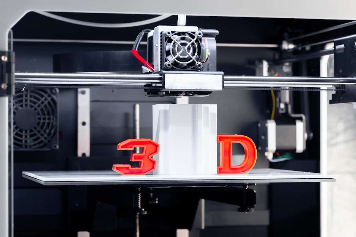 Close-up of 3D printer in black and white, with plastic '3' and 'D' in red.