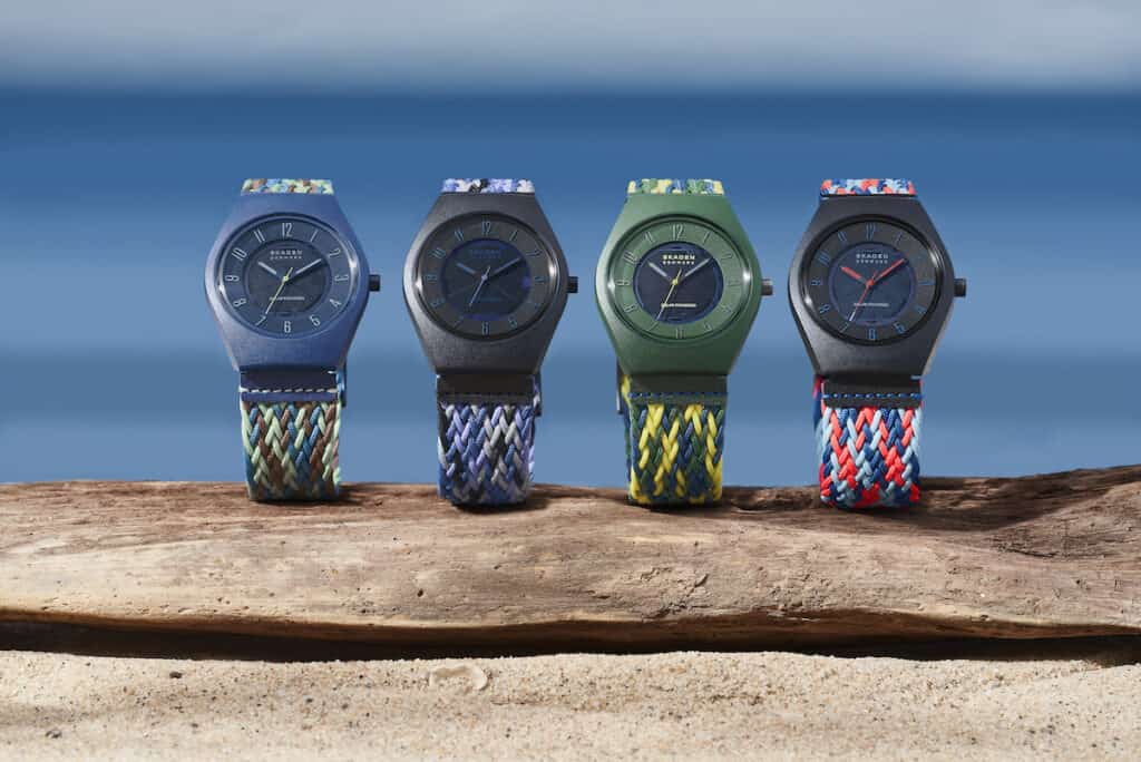 Samsø Series watches pictured in 4 bright colourways, stood upright on driftwood and natural sandy ground against blue sea or sky backdrop.