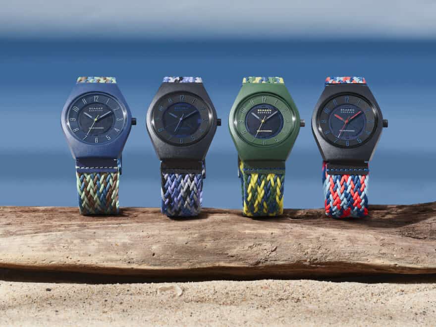 Samsø Series watches pictured in 4 bright colourways, stood upright on driftwood and natural sandy ground against blue sea or sky backdrop.