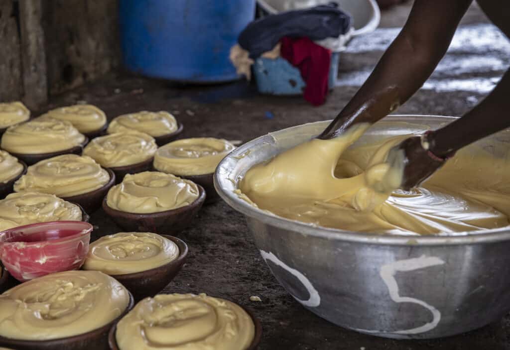 Yellow custard-like shea butter being stirred by hand in bowl. Photo credit: Makke Hussein.