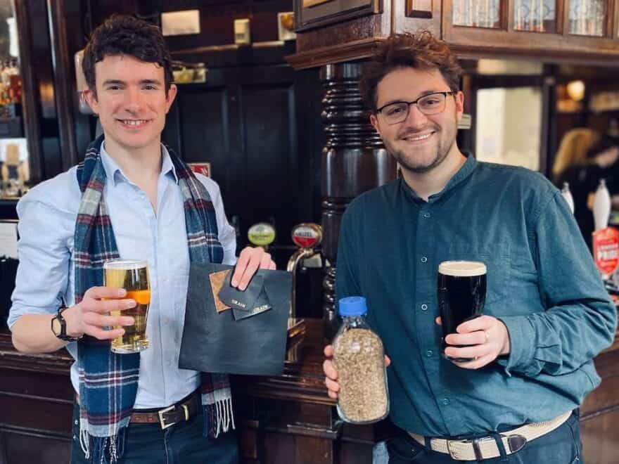 Arda Founders Edward TJ Mitchell and Brett Cotten pictured in pub holding glasses of beer, sample of leather alternative and bottle of spent grain.