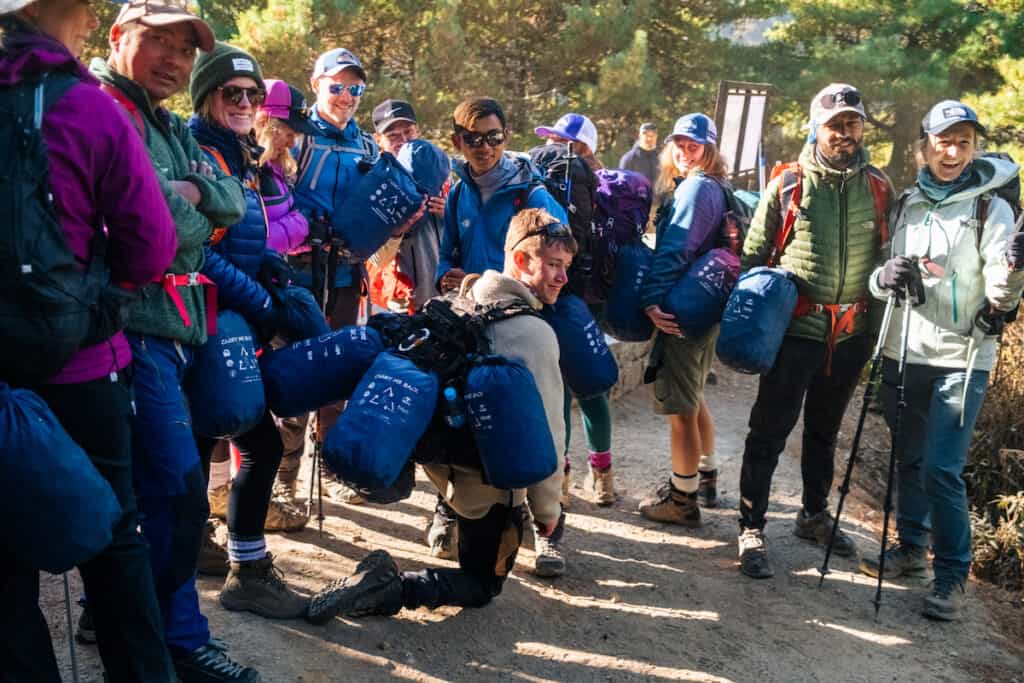 Group of trekkers holding and wearing blue 'Carry me back' bags.
