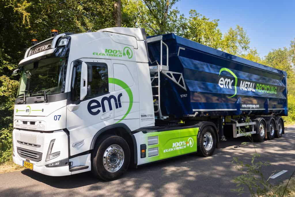 Volvo FM all-electric truck in white and blue livery, with EMR Metal Recycling branding down side, pictured on country road.