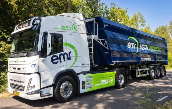 Volvo FM all-electric truck in white and blue livery, with EMR Metal Recycling branding down side, pictured on country road.