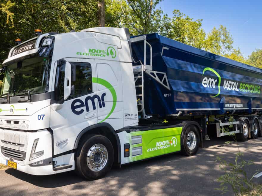 Volvo FM all-electric truck in white and blue livery, with EMR Metal Recycling branding down side, pictured on country road.