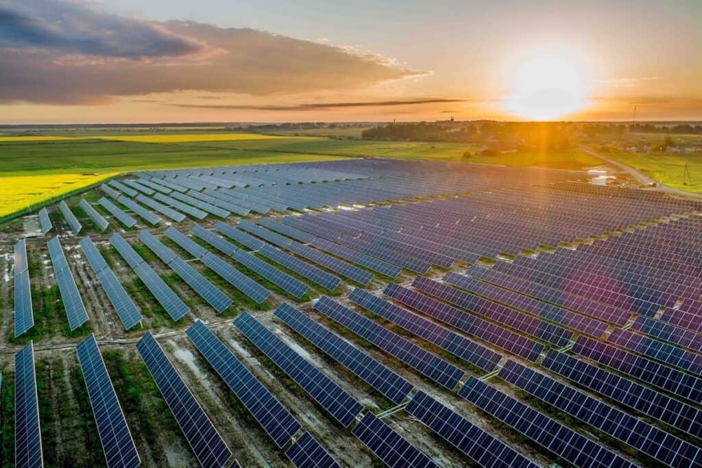 Green Genius solar power plant in Lithuania, with rows of solar PV panels pictured from above at sunset, surrounded by green fields.