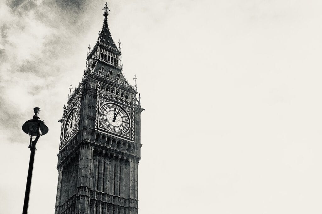 Black and white shot of clock tower housing Big Ben at Houses of Parliament, London.