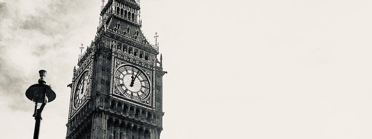 Black and white shot of clock tower housing Big Ben at Houses of Parliament, London.