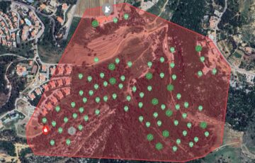 Aerial view of pilot site — wooded central area and residential surrounds, with red and green graphic overlay to indicate source of fire alert.