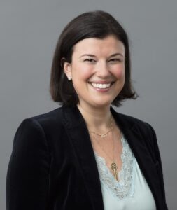 Portrait picture of Alexandra Mihailescu Cichon, Chief Commercial Officer at RepRisk, in dark jacket and pale blue top, against grey backdrop.