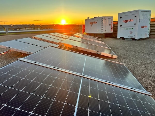 Ground-level solar PV at sunset, with Aggreko energy storage in back.