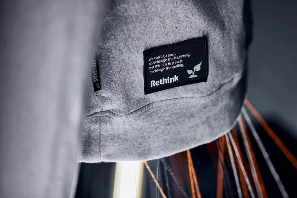 Grey garment with close-up on 'Rethink' label stating: 'We can't go back and change the beginning, but this is a first step to change the ending.'