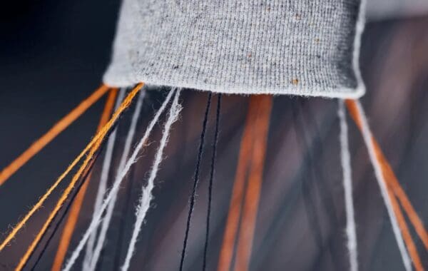 Close-up of orange and grey threads strung out of garment fragment.