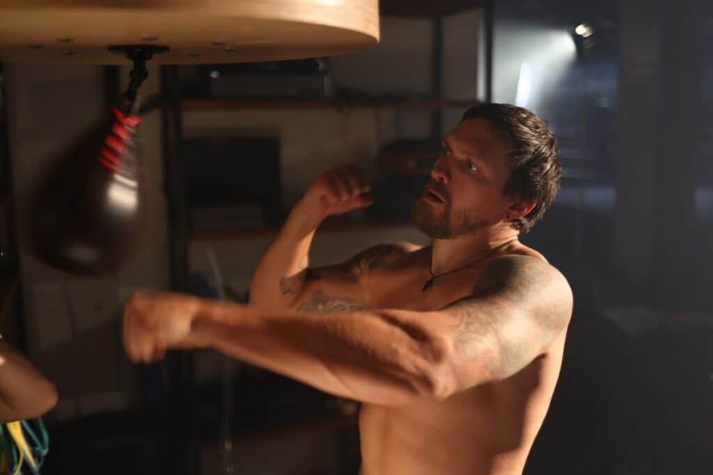 Close-up of bare-chested boxer Oleksandr Usyk training with speed bag.
