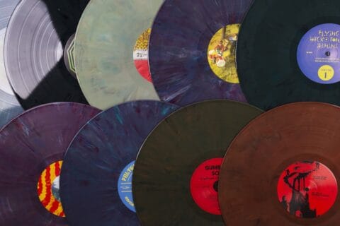 8 black and multi-coloured vinyl records laid overlapping in two rows.