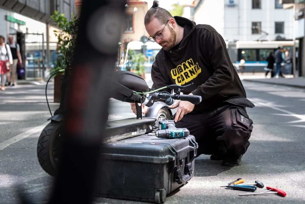 Urbancorner staff member on street with toolkit fixing electric scooter.