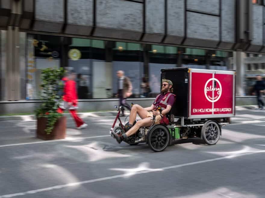 Four-wheel Pling cargo bike on street, with delivery driver up front.