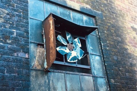 Rusted industrial extraction fan in external wall.