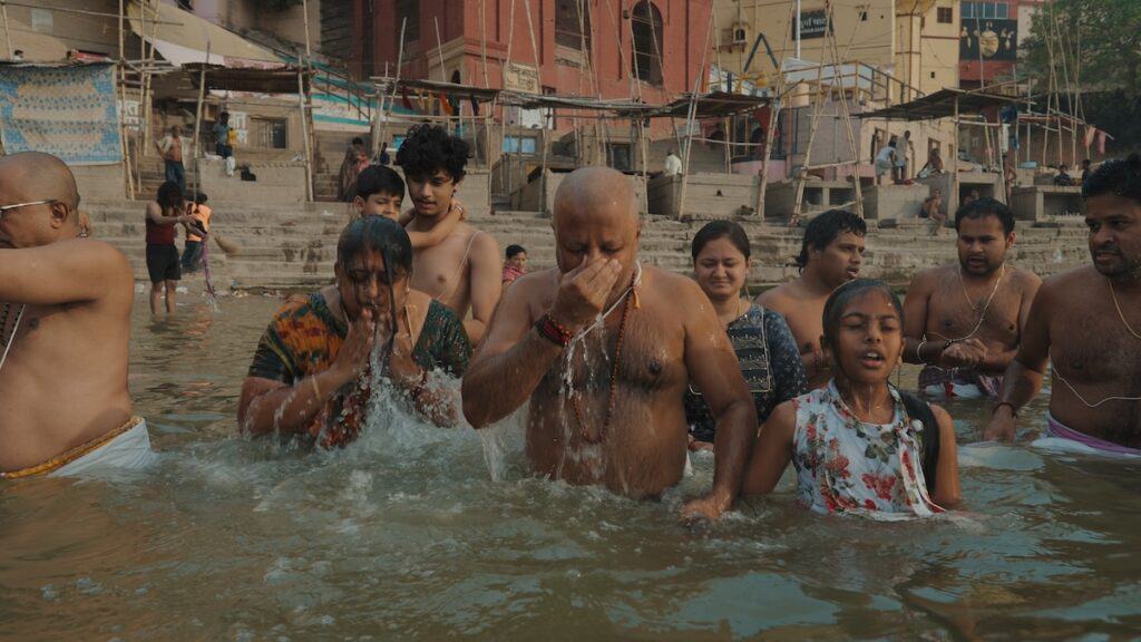 People of various ages and different genders bathing in waters of Ganges River.