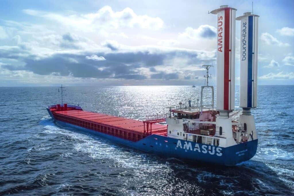 Large Amasus-branded Eems Traveller cargo ship pictured at sea, with pair of vertical suction sails to stern.