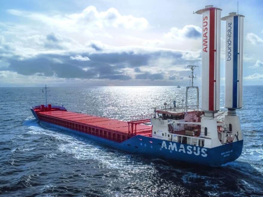 Large Amasus-branded Eems Traveller cargo ship pictured at sea, with pair of vertical suction sails to stern.