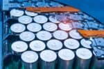 Close-up of lithium-ion battery pack module, revealing grid of upright chrome-coloured cylinder-shaped batteries, sat within blue and orange casing.