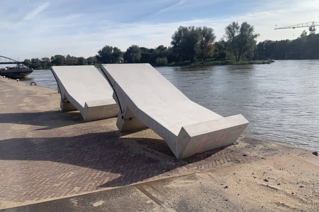 Pair of precast concrete L-shaped components in sunshine on quayside.