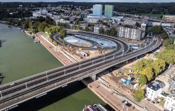 Aerial view of works to bank or river in Arnhem, with road bridge running across, plus blue and white skate park around and under carriageway.