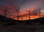 Wind farm turbines pictured in silhouette against colourful sky at sunset.