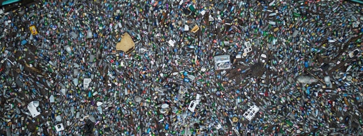 Aerial view of floating (mostly plastic) trash filling area trapped behind blue cordon of Interceptor Barrier, beyond which seawater is garbage-free.