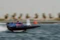 Aoki Racing Team RaceBird boat in blue and pink colours speeding in elevated mode across water, with background blurred.