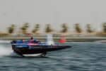 Aoki Racing Team RaceBird boat in blue and pink colours speeding in elevated mode across water, with background blurred.