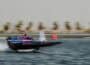 Aoki Racing Team RaceBird boat in blue and pink colours speeding in elevated mode across water, with background blurred.