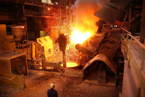 Bright orange glow as furnace rains sparks around industrial facility.