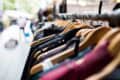 Close-up at hanger level of clothes on a rail, in focus on right foreground, with background blurred.