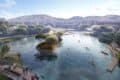 Illustration shows large lake development with mountains behind, tree islands in centre, canoes on water, pedestrians on walkways and bridges.