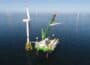 Neptune installation deck with crane shown at sea in green and white DEME livery, in position beside turbine with offshore wind farm behind.