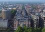 Aerial cityscape of central London, green trees in foreground, Mandarin Oriental hotel front and centre, rotunda building to left and view down long straight street in the middle of the shot, receding into distance.