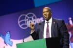 Executive Secretary Dr Luthando Dziba in dark suit and striped tie speaking from green lectern at IPBES 12, logo behind.