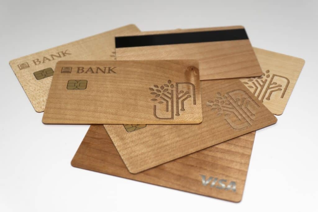 Selection of wooden bank cards fanned out on white background, with words BANK and VISA in corners, plus one showing magnetic strip on reverse.