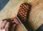 Close-up of griddled-brown mycelium steak being cut with a knife on wood chopping board to show reddish-pink interior texture similar to beef.
