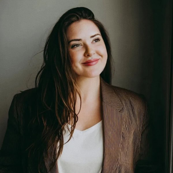 Professional profile picture of Grace Waters, smiling and looking up to her left, long dark hair down, wearing brown jacket over white blouse.