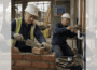 Square ChatGPT of construction site, ageing workers in hard hats; bricklayer in high-vis (L) and plumber in boiler suit (R); faded duplicate 25% panels L & R.