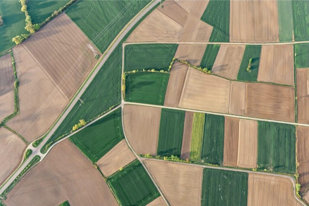 Aerial shot of patchwork of green and brown farm fields.