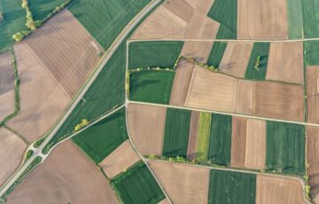Aerial shot of patchwork of green and brown farm fields.