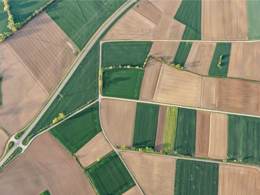 Aerial shot of patchwork of green and brown farm fields.